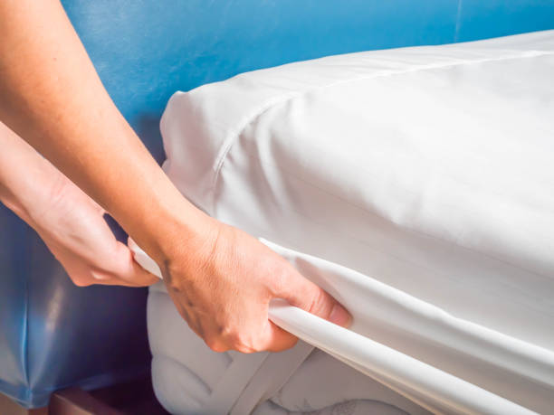 Woman is putting the bedding cover or mattress pad on the bed or putting off for cleaning process.